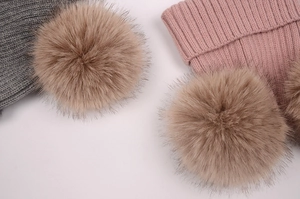 Détail de bonnets tricotés rose et gris avec deux pompons en fausse fourrure marron