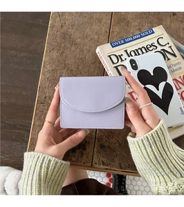 Hand holding a lavender PU leather card holder over a wooden table for size demonstration