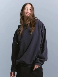 Close-up of oversized hoodie featuring metallic rivet details on the sleeves and shoulder