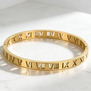 Close-up of gold hollow Roman numeral bangle on a minimalist white marble background