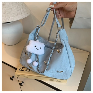 Detail of light blue nylon shoulder bag with butterfly chain and plush cloud charm decor