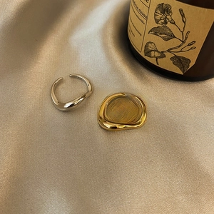 Minimalist wave-shaped open rings in gold and silver finish on silk background