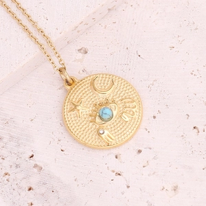 Macro shot of gold sun moon star pendant with turquoise inlay on textured stone
