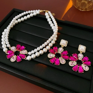 Dettaglio della collana di perle a doppio strato con fiore rosso rosa e pendente dorato