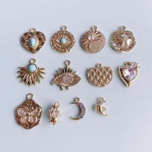 Close-up of gold alloy charms including evil eye, heart and moon with inlaid crystals