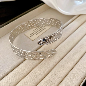 Macro shot of silver open cuff bracelet with intricate floral filigree on velvet tray