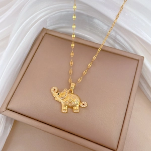 Close-up of a gold elephant pendant necklace with shimmering crystals on a beige jewelry box