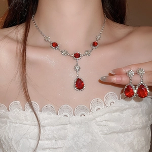 Dettaglio del set collana e orecchini con pietre rosse a goccia su una modella