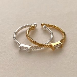 Dettaglio degli anelli a corda intrecciata oro e argento con zircone rettangolare incastonato