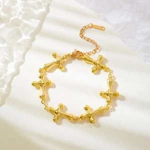 Detail of gold-plated cross bracelet showing the extension chain and secure clasp closure