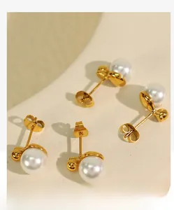 Detailed macro shot of elegant white pearl stud earrings with polished gold metal bases