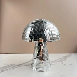 Close-up of a silver mirrored mushroom disco ball reflecting light on marble surface
