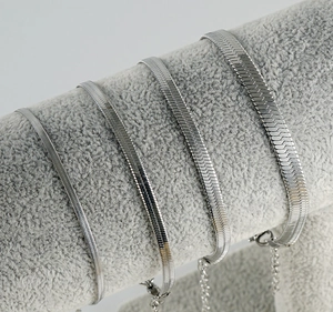 Detail showing four widths of silver blade chains on a gray display stand with lobster clasp