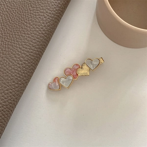 Detailed shot of acetate heart hair clip featuring marble pink and gold textured finish