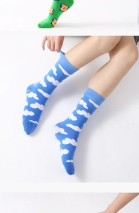 Detail view of blue cotton socks with white cloud pattern and green floral accents
