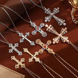 Flat lay of layered cyberpunk cross necklaces with pearls and gemstones on brown fabric