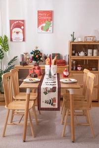 Festive Christmas table runner with trees and gift patterns featuring red plaid edges