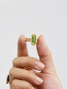 Vue macro d'une bague torsadée dorée ornée d'une pierre précieuse ovale vert émeraude