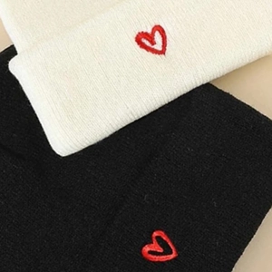 Winter knitted beanies in black and beige featuring red heart embroidery for couples