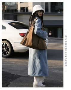Street style shot of a brown large capacity tote bag worn with a blue winter coat
