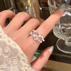 Dettaglio di un elegante anello a doppio strato con perle e strass sulle dita