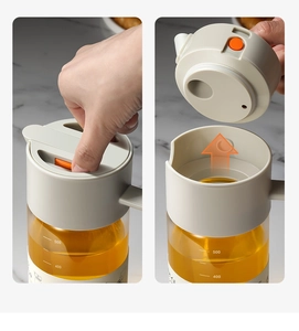 Détail d'un huilier en verre montrant le couvercle à bouton orange et l'échelle graduée