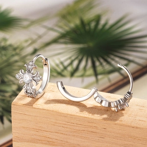 Silver cross hoop earrings with cubic zirconia stones on a natural wooden background