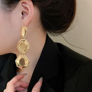Vue détaillée de boucles d'oreilles dorées géométriques avec trois formes hexagonales