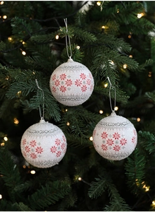 Close-up of white Christmas foam balls with red snowflakes on a festive pine tree branch