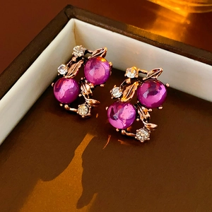 Detail view of vintage gold earrings with purple gemstones and sparkling rhinestones
