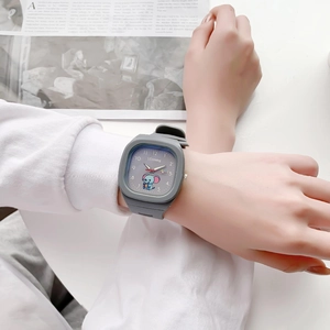 Detail of grey square watch with elephant pattern on silicone strap against a magazine
