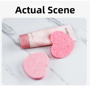 Pink heart-shaped compressed wood pulp sponges next to a 100ml facial cleanser tube