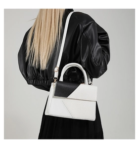 Chic black and white crocodile pattern handbag held by model in black leather jacket