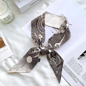 Detail of silk scarf with female silhouettes and sun motifs tied in a bow on a magazine