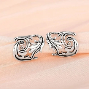Macro shot of vintage oxidized silver leaf ear cuffs with intricate hollow filigree details