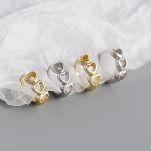 Nahaufnahme von vier minimalistischen Herzringen aus S925 Silber und Gold auf weißem Papier