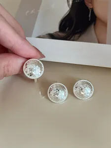 Detailed close-up of silver round stud earrings with hammer texture and rope-edged trim