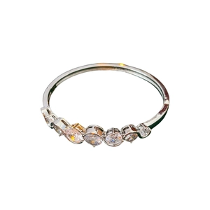 Minimalist silver bangle featuring seven various sized clear zircons on a white background