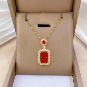 Close-up of gold necklace with rectangular red gemstone and pavé zircon detailing