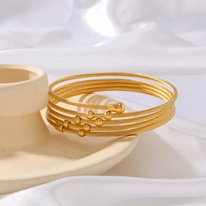 Bracciale a spirale dorato minimalista con perline lucide su pregiato sfondo in seta