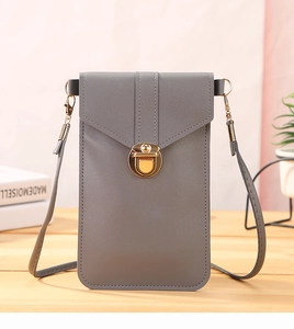 Detail of grey crossbody phone bag with a gold metal lock and slim strap on a desk