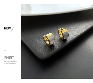 Detail shot of golden titanium steel earrings featuring white mother-of-pearl inlays