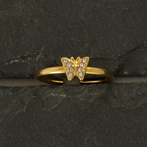Macro shot of 18k gold butterfly ring wings with sparkling diamonds on stone background