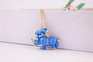 Close-up of golden rhinoceros pendant with blue enamel and sparkling rhinestones
