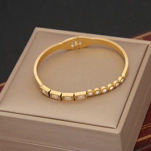 Detail view of gold stainless steel bangle with rectangular zircon inlays and spring clasp