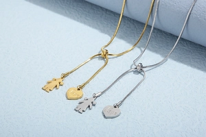 Detail of adjustable snake chain necklace with gold heart and girl silhouette charms