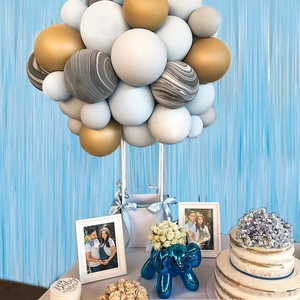Blue fringe curtain backdrop with pastel balloons for birthday party scene setup