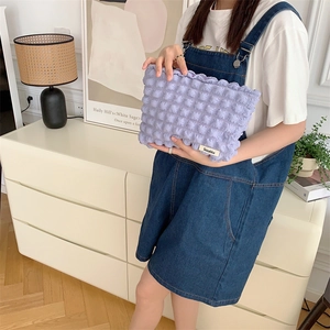 Close-up of purple bubble texture canvas cosmetic bag with Sayakla label held by model