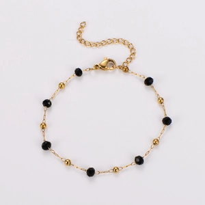 Détail du bracelet doré avec perles noires facettées, fermoir mousqueton et chaînette