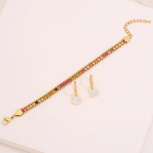 Detailed macro view of gold-plated bracelet with colorful zircons and heart earrings